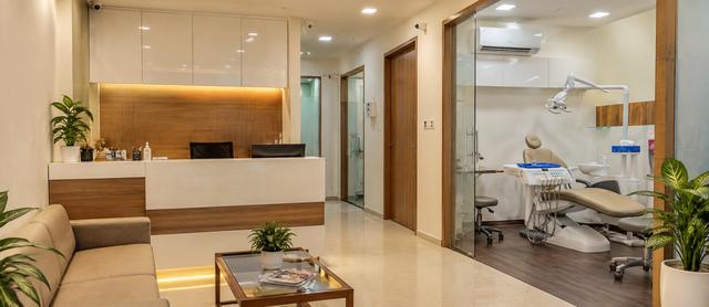 Clinic reception with a dental treatment room behind glass